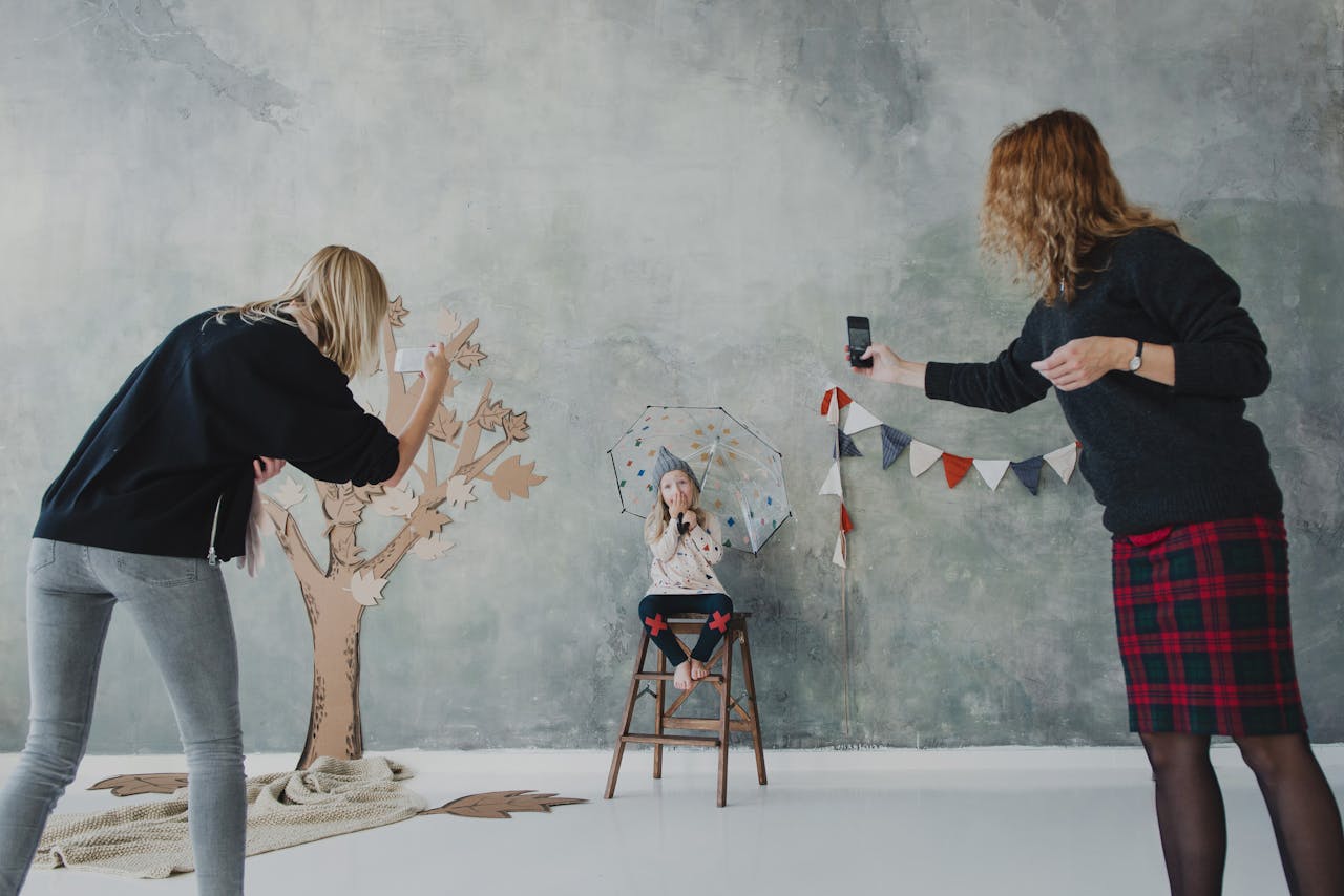 A child holding an umbrella posing for a photo session in a creative studio setup.